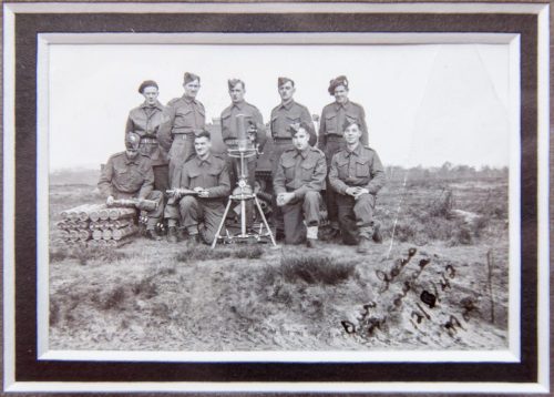 A black and white photo of a company of soldiers posing on a field in England prior to departing for Dieppe. Morris Greenberg is in the front row, second from the left.