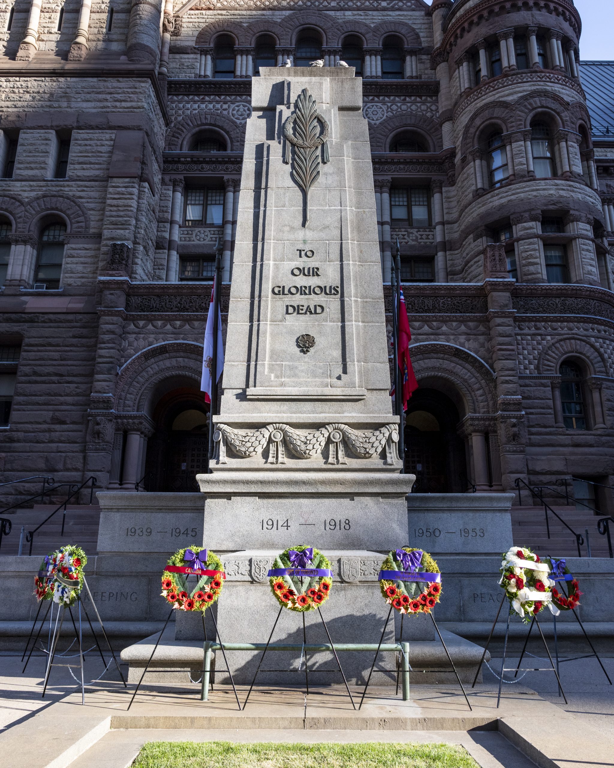 A photo of the Old City Hall Cenotaph with 8 wreaths on stands in front of the cenotaph.