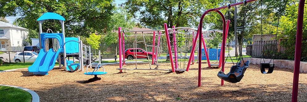 Photo of the existing playground at Primula Parkette, featuring a slide, swing set and climbing structure.
