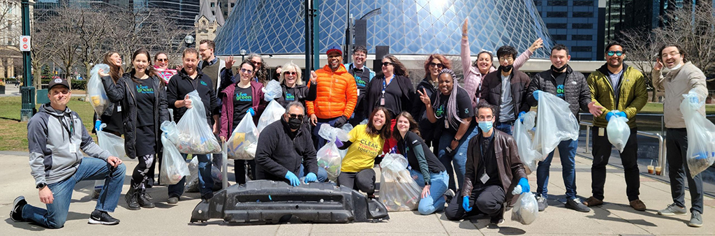 A team of people holding garbage bags and celebrating having just completed a waste cleanup initiative.