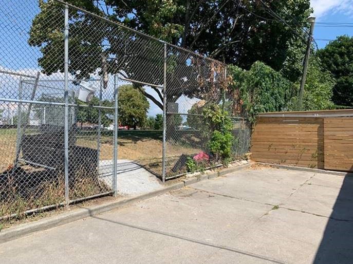 Image of the fenced entrance to the park from the Floyd Street laneway near the east side of the park. 
