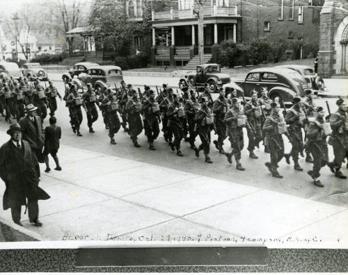 A black and white photo of soldiers parading down Bloor Street with onlookers watching