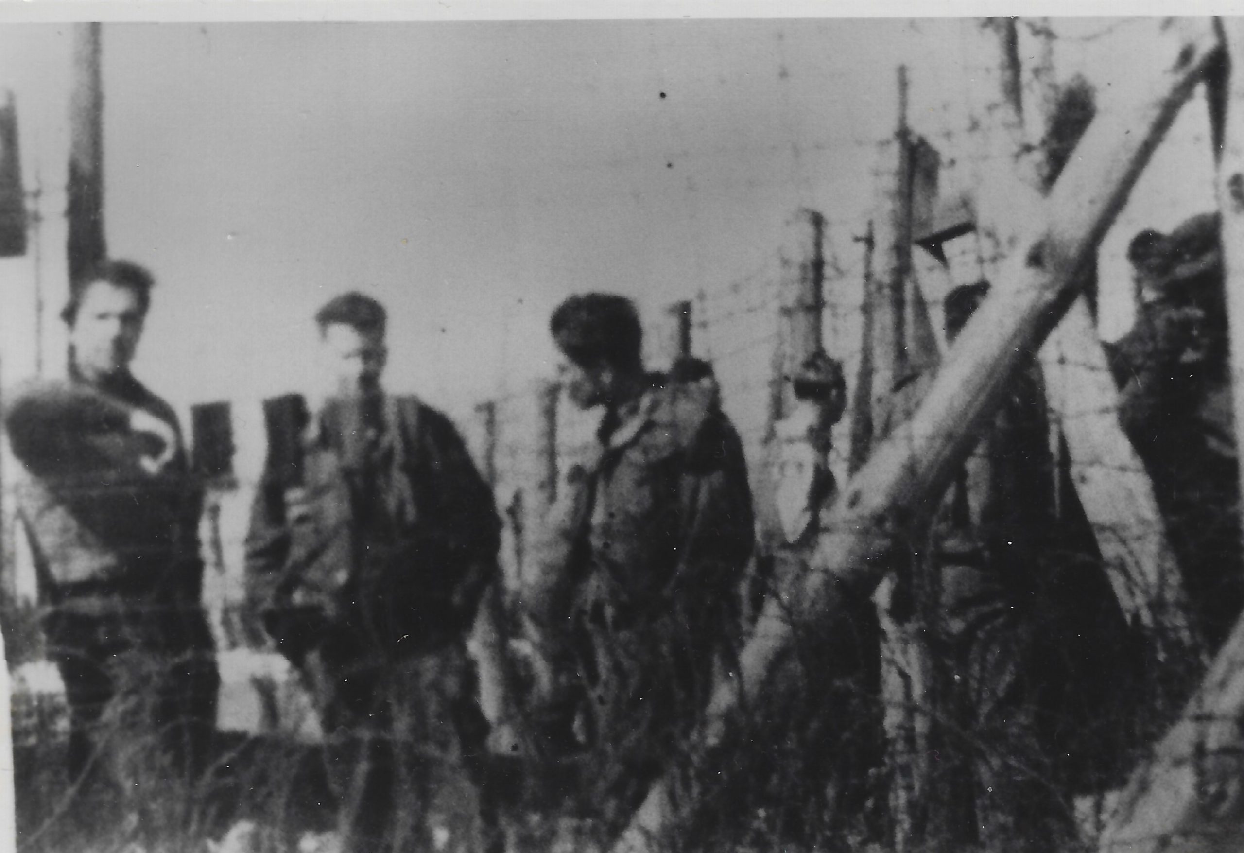 Image of people behind the barbed wire at a Prisoner of War Camp