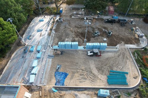 An aerial photograph of the construction at Dufferin Grove Park showing the progress of the ice rinks. The site is a construction zone with dirt and rounded concrete borders showing the outline of the rinks. 