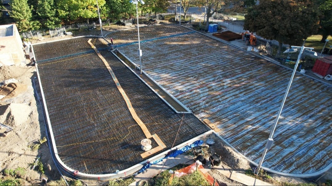 Image taken by a drone of the Hockey Rink and Leisure Pad from above. Refrigerant piping and steel reinforcement visible within the rinks, with earthwork in progress within the future public plaza west of the Leisure Pad.