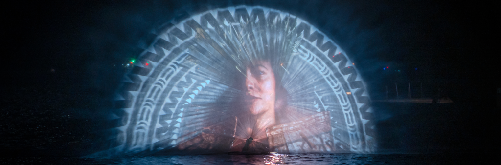 Portrait of a woman projected onto smoke over top of water at night