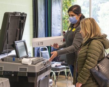 polling place workers reviewing ballet scanning equipment