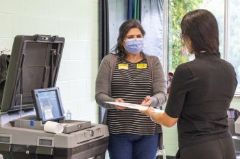 Polling station workers placing a ballet into the ballet scanner