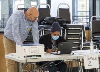 Polling station voter registration table with two people viewing a computer