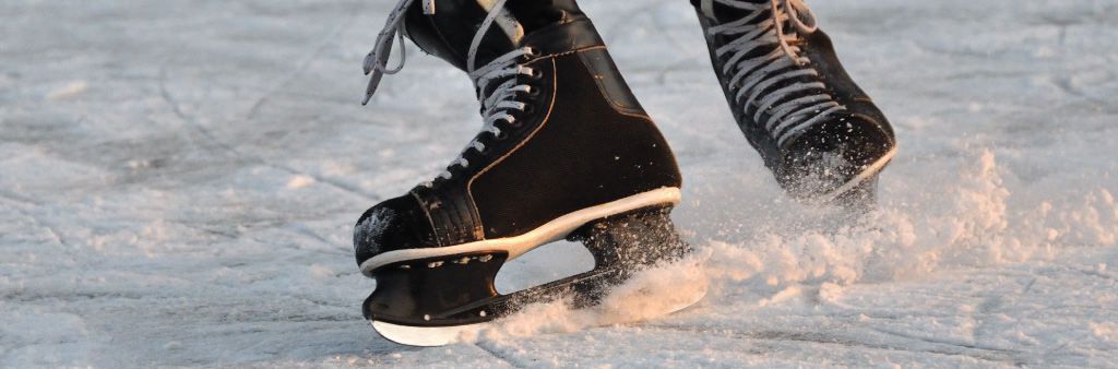 Close-up of hockey skates stopping quickly on the ice