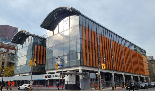 Exterior view of St. Lawrence Market, North Building featuring an arched glass facade and orange siding.