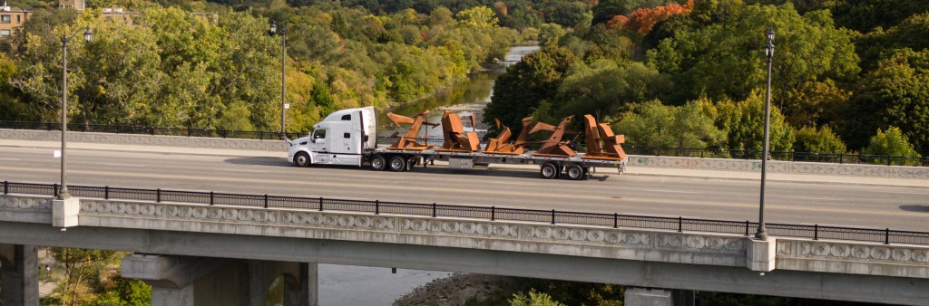 TRUTH artwork on flatbed truck driving across a bridge