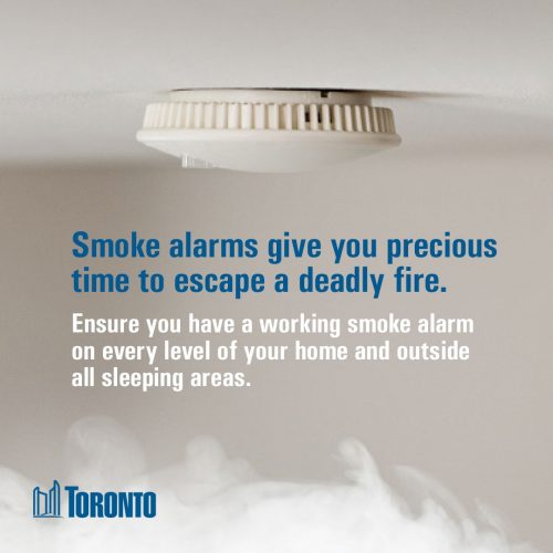 Smoke alarm on ceiling with smoke and text beneath