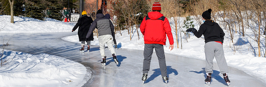 Youth skating on an outdoor ice rink trail on a sunny day