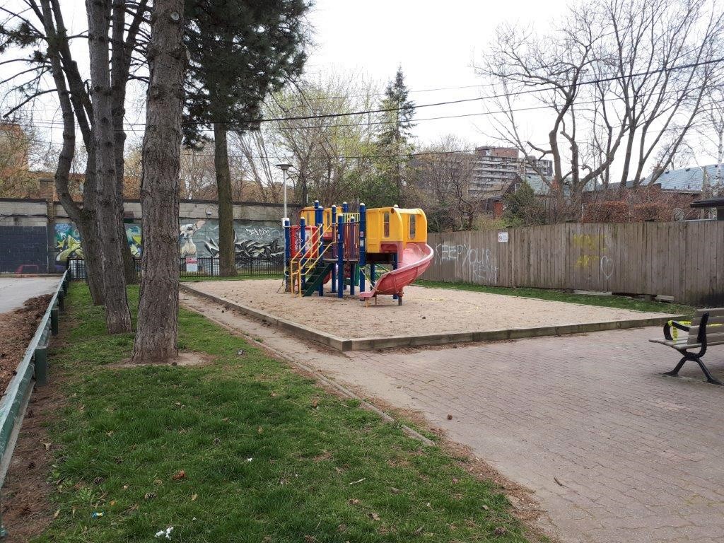 A photograph of Melbourne Avenue Parkette Playground before improvements, which shows a play structure on top of a large sand box.