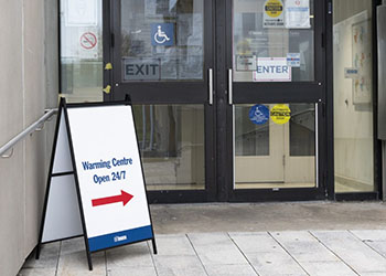 A sign indicating that warming centres are open with an arrow pointing to door