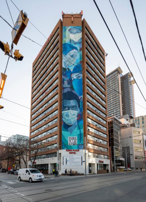 Photo of the 18-storey building with graffiti of front-line workers on the side.