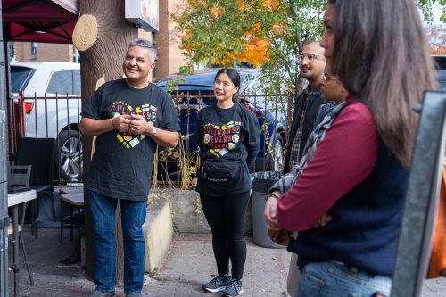 A small group of people standing in a group on the sidewalk