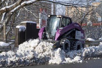 cropped view of a sidewalk plow removing snow on a residential sidewalk