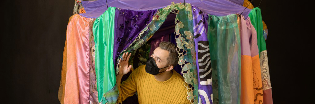 Fabric artwork with person inside pushing back curtain. French, Œuvre d'art en tissu avec une personne à l'intérieur poussant un rideau de côté