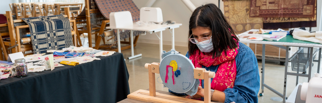 Person seated in a crafting room working on textiles