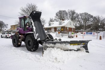 a snow plow clearing snow from a road on a residential street