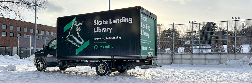 A black and green truck with a graphic of a skate on it, with Skate Lending Library printed on the side and back
