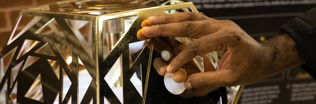 Hand places wooden ball into opening in metal polygon