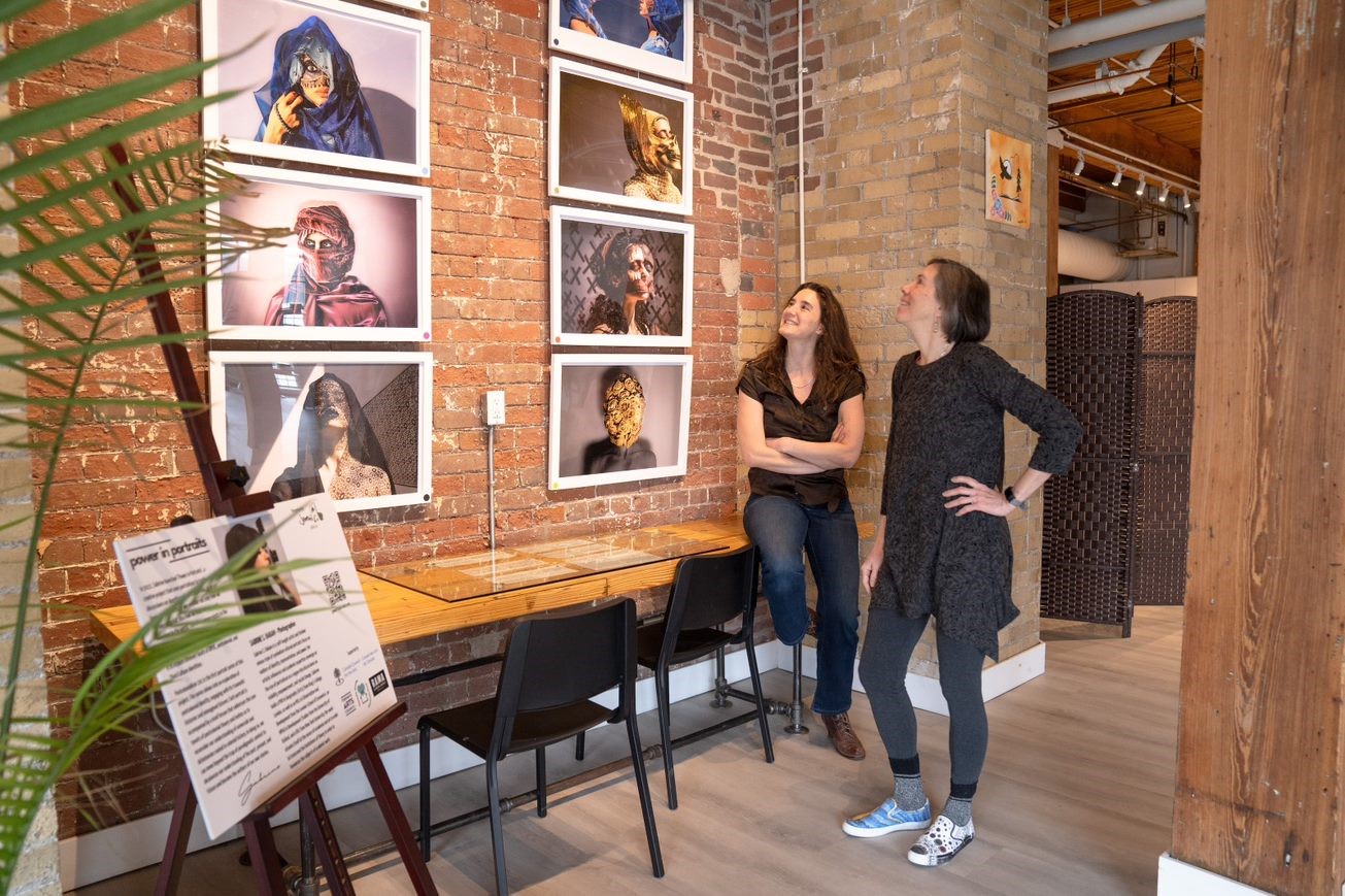 Two people look up at wall of artworks