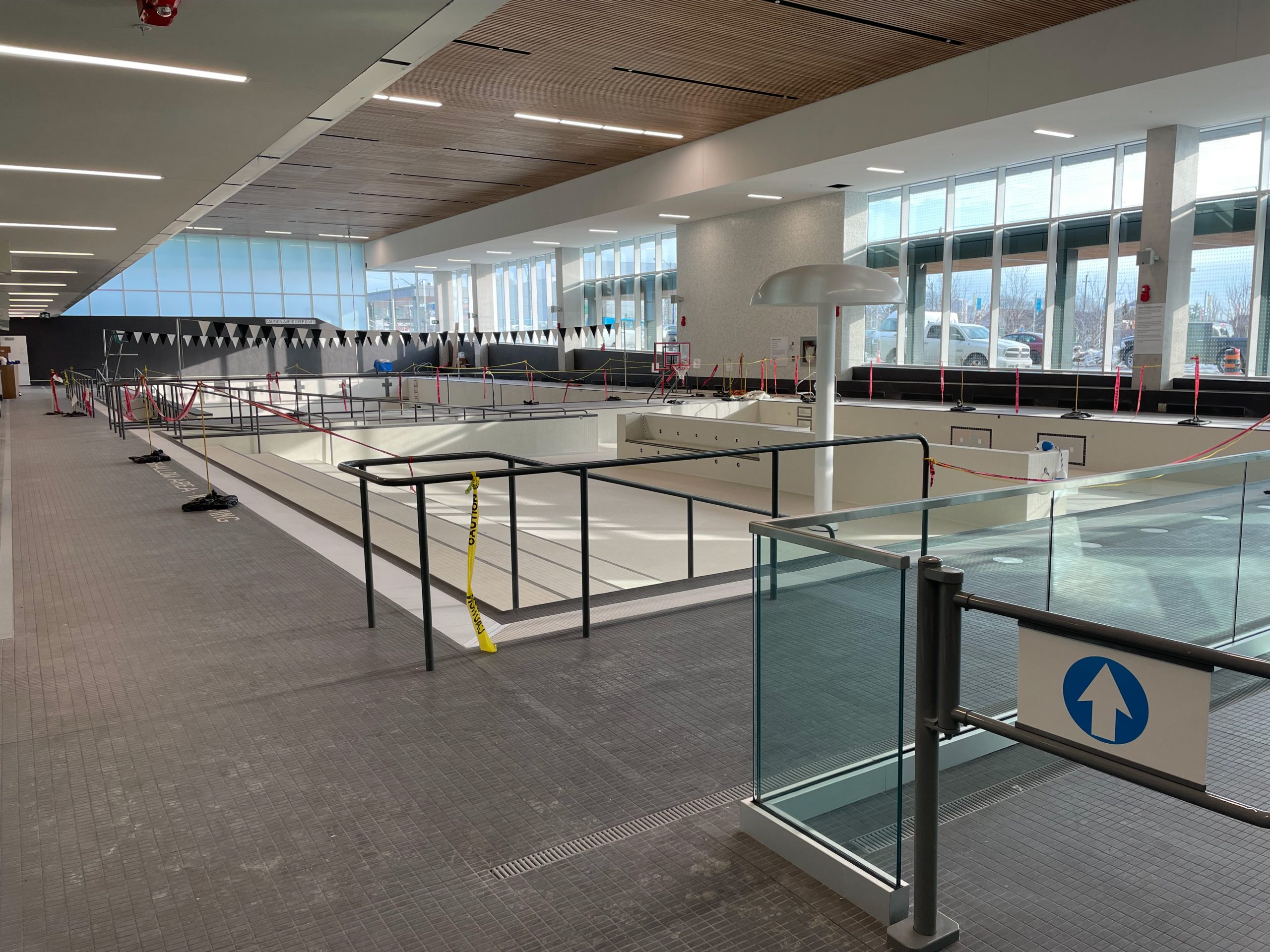 A photograph of the interior swimming pool area of the new Ethennonnhawahstihnen' Community Recreation Centre & Library while under construction, which shows an empty leisure pool with a water play feature in the foreground. 