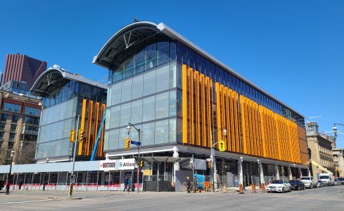 Exterior view of St. Lawrence Market, North Building featuring an arched glass facade and orange siding.