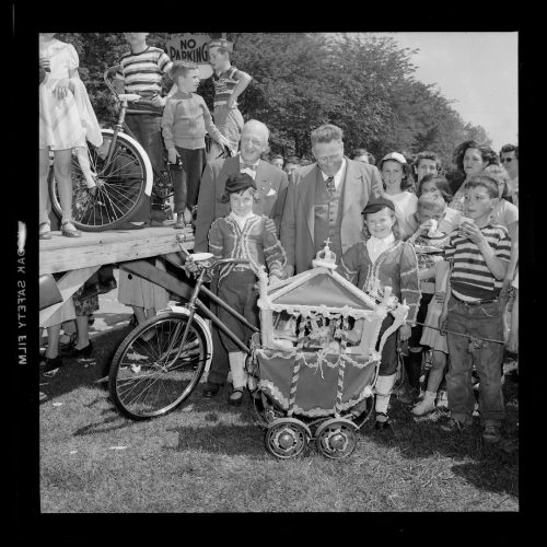 Image depicts children with bicycles and a miniature model of the Gold State Coach