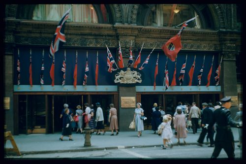 Photograph depicts store entrance decorated with Royal Coat of Arms, Union Flags and Canadian Red Ensigns