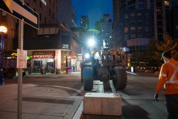 Construction equipment puts concrete block down on road.