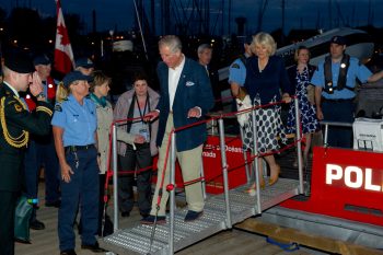  Prince of Wales and His Majesty walking on a boat ramp, Canadian flag in the background