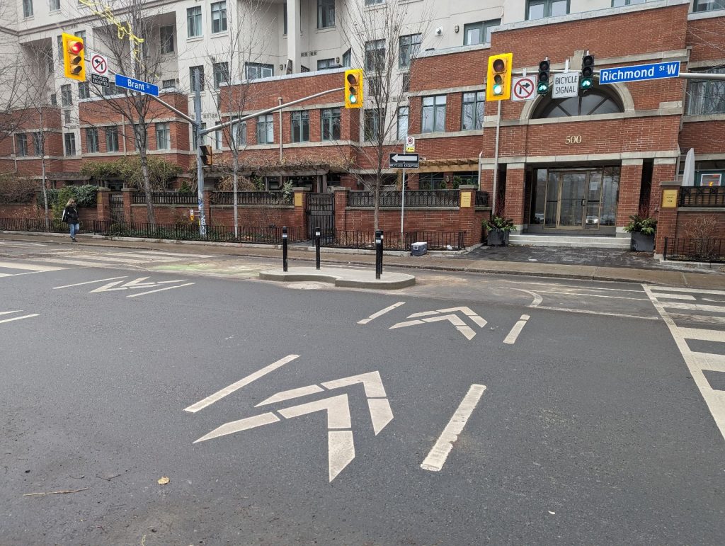 Concrete curb island located at the north side of Richmond Street West at Brant Street.