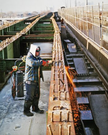 Image depicts man cutting metal