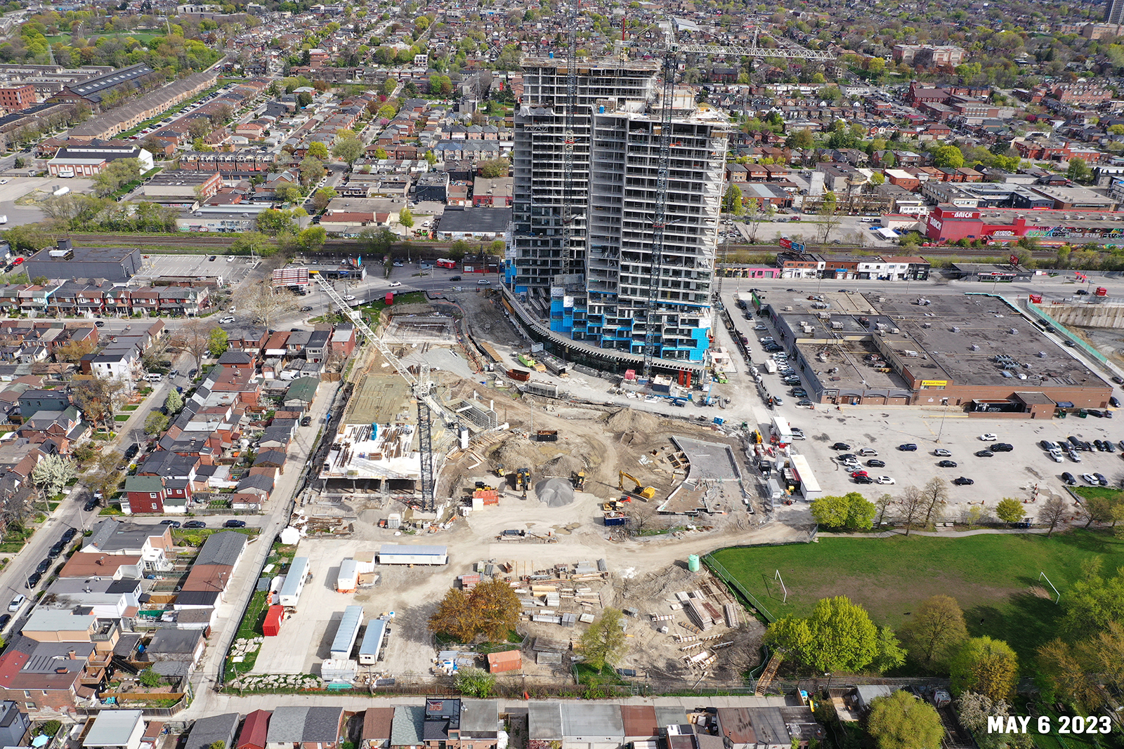 An aerial photograph of the construction site at Wallace Emersion Community Centre on May 6, 2023, which shows a large crane at the centre of the construction site and construction equipment. The community centre structure under construction is show just south of Dupont Street. 
