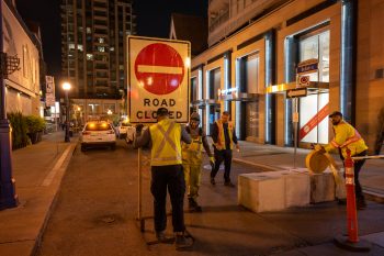 Crews install road closed sign