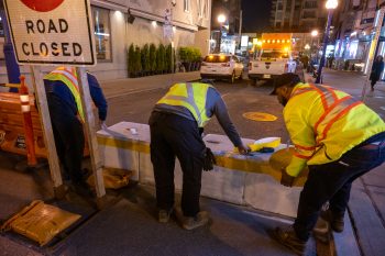 Crews install reflective tape on concrete bollard