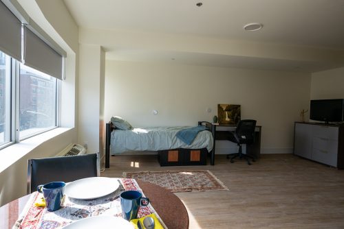 A photo of an affordable rental home at 222 Spadina Ave. There is a bed, a dining table and a TV.
