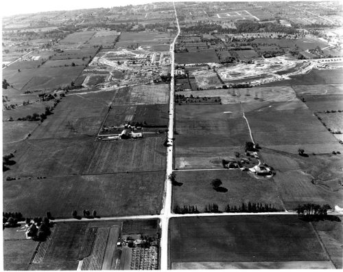 Image depicts oblique aerial view of rural road intersection taken from aircraft