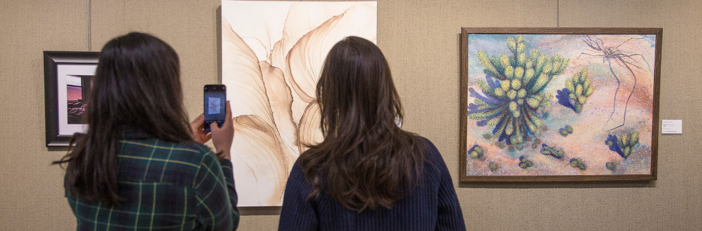 Two people looking at paintings on the wall