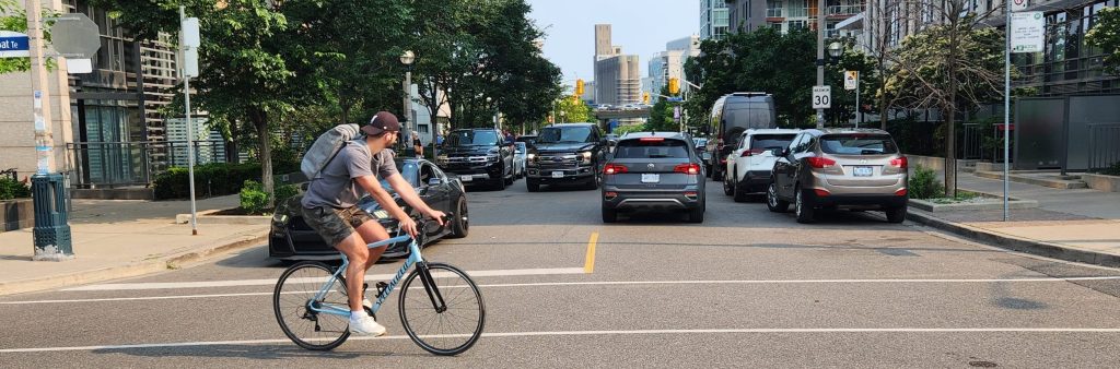 Photo of Dan Leckie Way looking South. One cyclists is crossing the street.