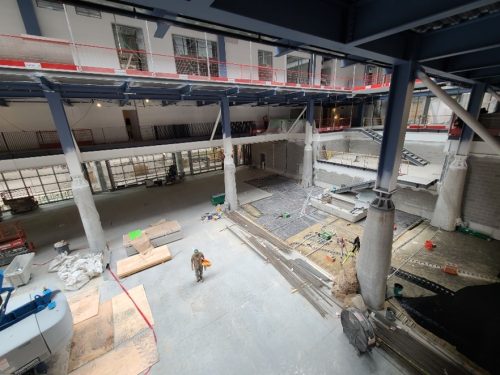 Interior view of St. Lawrence Market showing a construction worker, wood flooring and the second level.