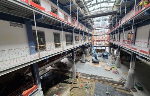 Interior view of St. Lawrence Market under construction with a crane and construction tools.
