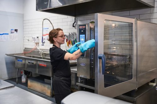 Person puts tray into oven in professional kitchen