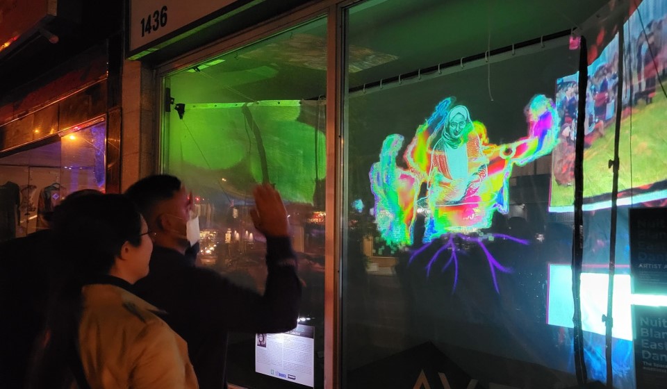 People look and wave at art projection in shop window