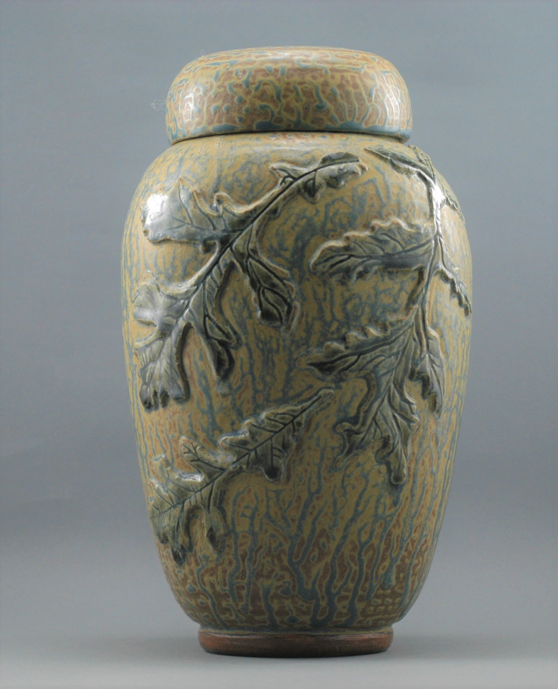 Ceramic artwork of vase decorated with three leaves and lid