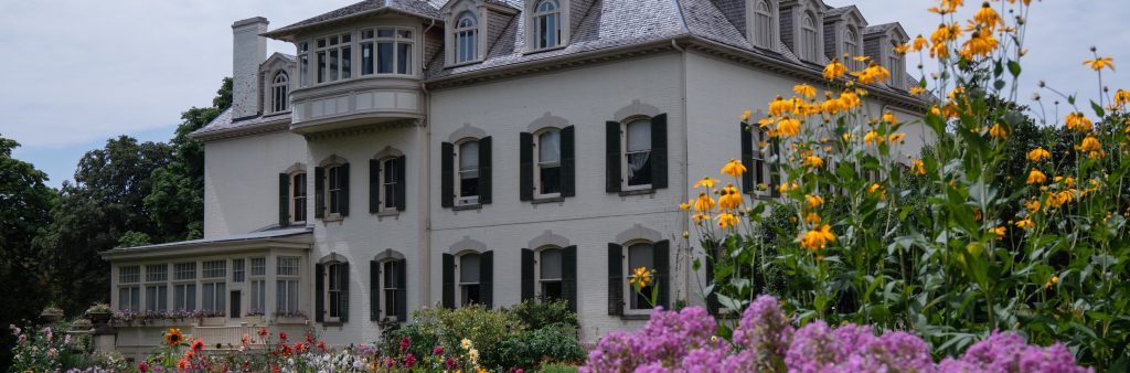 Exterior of three story manor house with garden flowers in foreground